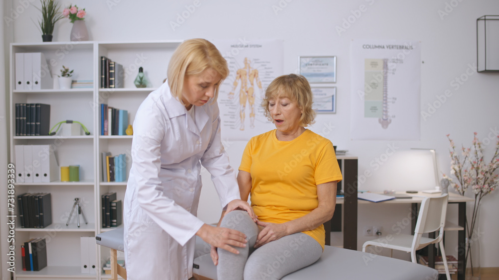 A doctor examines a female patient experiencing pain in her injured leg, providing treatment A doctor examines a female patient experiencing pain in her injured leg, providing treatment