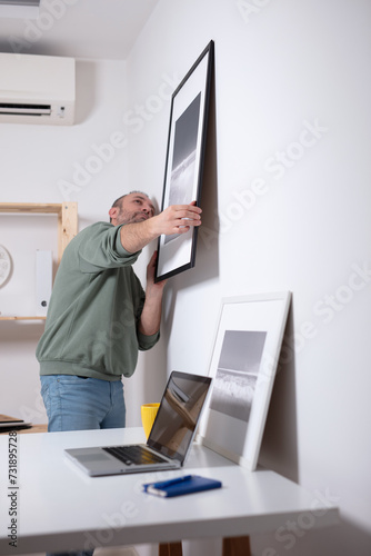 Man hanging pictures on the wall.