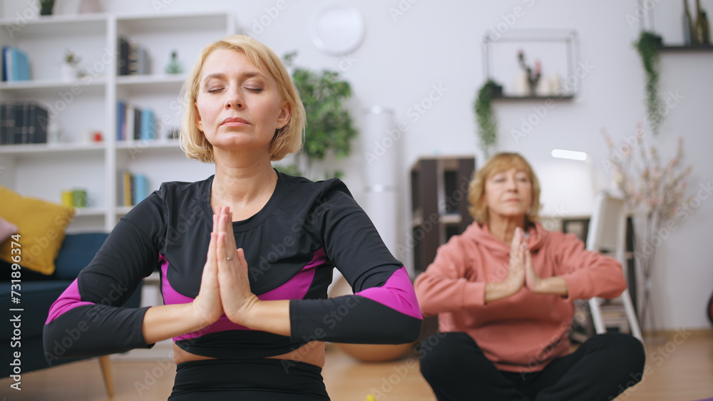 A yoga teacher and a mature client practice asanas and breathing exercises together