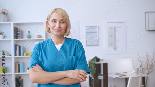 Portrait of a pleasant female doctor smiling at the camera, with her arms crossed, showcasing professionalism © Synthex🇺🇦