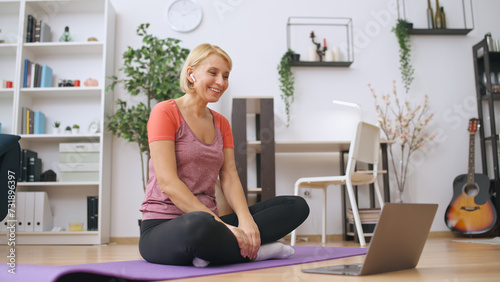 A smiling fitness trainer prepares for an online lesson, ready to train a client via video call