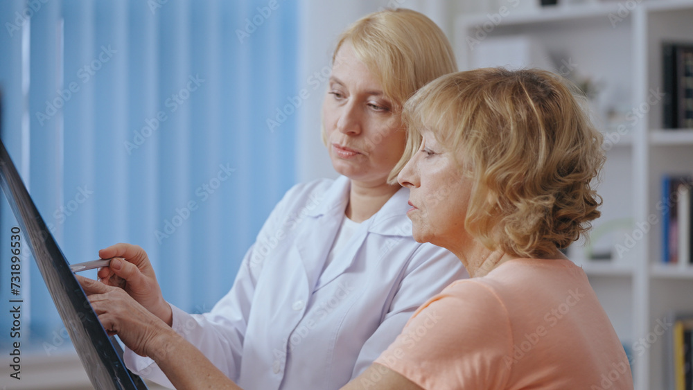 Fototapeta premium A doctor and her senior patient review an x-ray image during a medical consultation