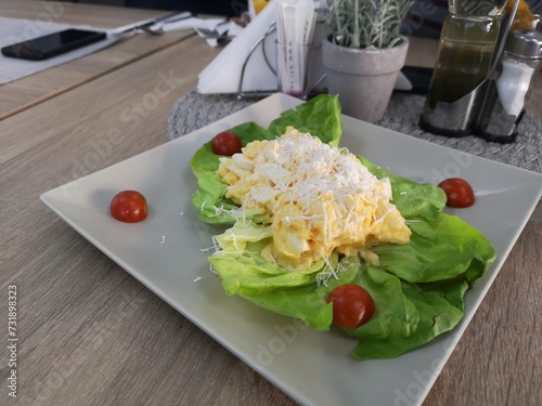 A pristine white plate adorned with vibrant green lettuce and juicy red tomatoes, creating a fresh and appetizing display.