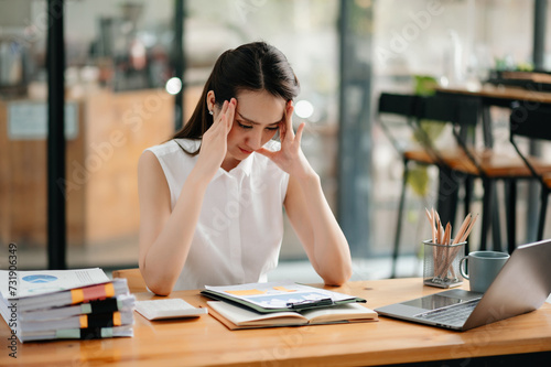 Asian woman feeling migraine head strain.Overworked businesswoman financier while working