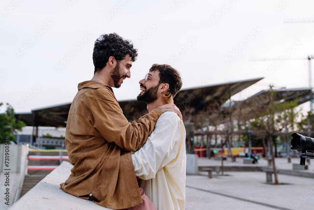 Positive gay couple hugging on street during date