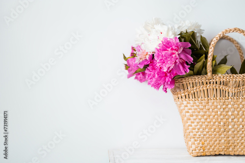 Fototapeta Naklejka Na Ścianę i Meble -  Beauty fashion closeup  with women's straw bag with peonies .Peony summer flowers bouquet. Lifestyle photo with flowers and a copy space.