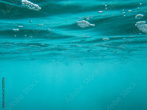 Burbujas de color azul profundo y peces bajo la superficie del agua. Fotografía de la superficie del agua en el Mar Mediterráneo tomada desde abajo.
