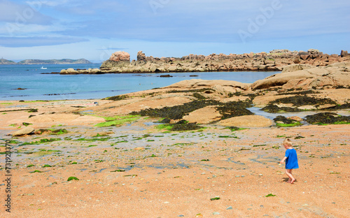 Little child (unrecognizable; back view) playing at Pink Granite Coast. Brittany, France. photo