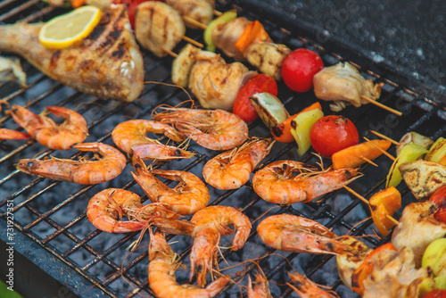 Shrimp, vegetables and fish are fried on a barbecue. Selective focus.