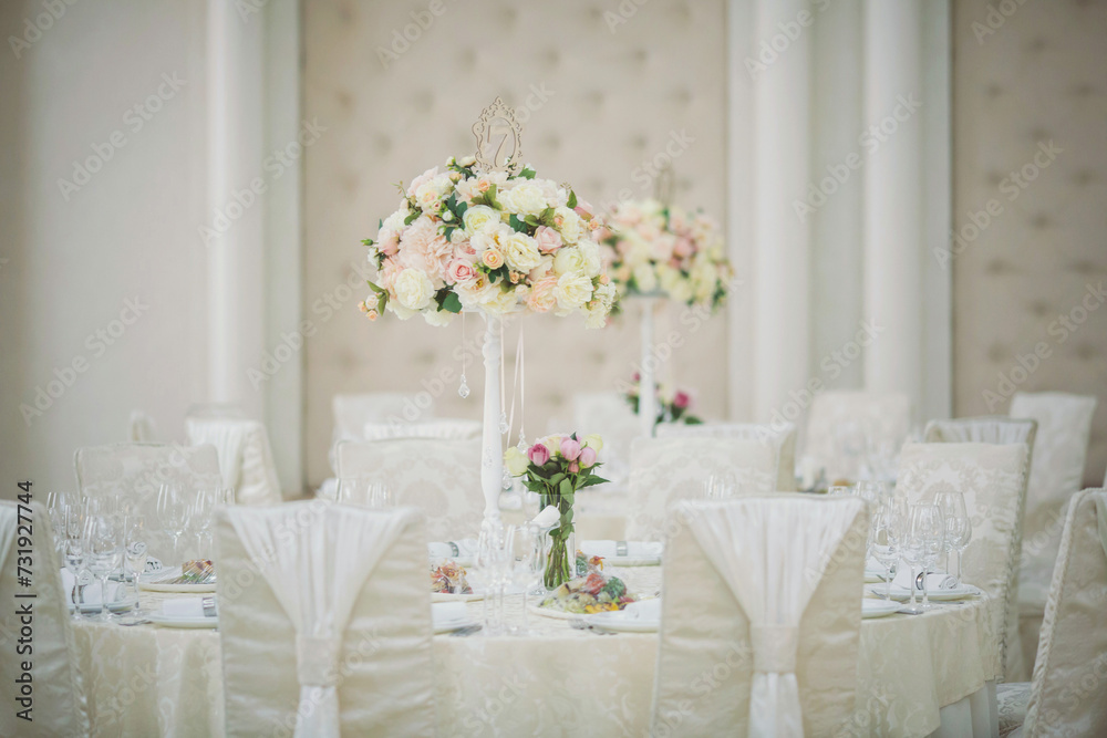 Beautiful flowers on table in wedding day. Table decor with flowers table numbers and candles. Boquet of flowers on arranged table. Beautiful flowers on table in wedding day. Table decor with flowers table numbers and candles. Boquet of flowers on arranged table.