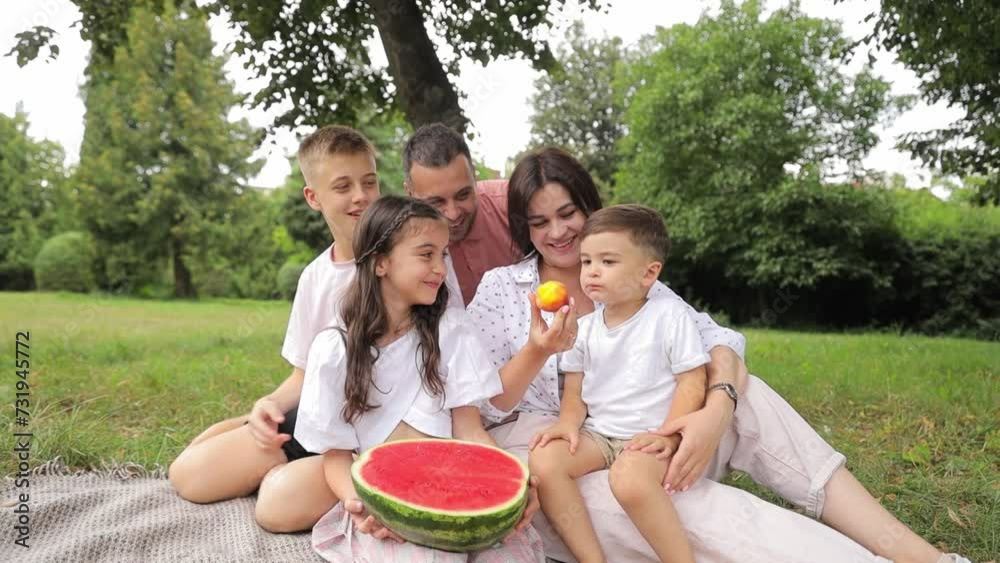 A family is having a picnic in the park and eating watermelon A family is having a picnic in the park and eating watermelon