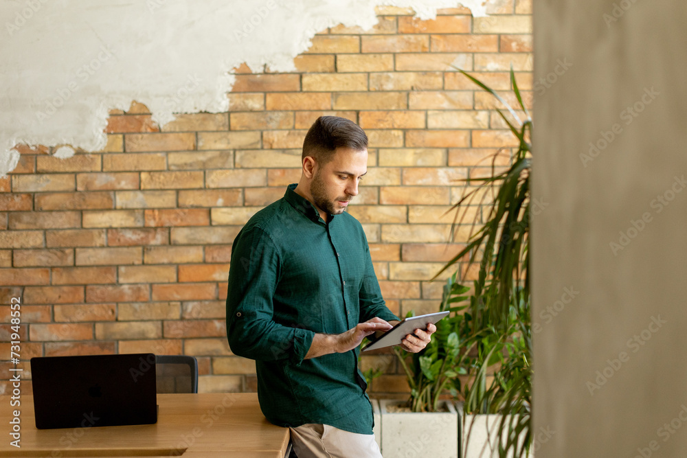 Smiling Man With Tablet in a Modern Brick-Walled Office Smiling Man With Tablet in a Modern Brick-Walled Office