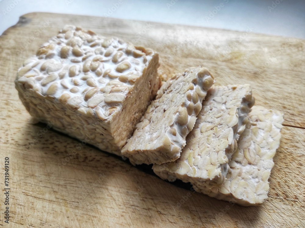 Sliced ​​raw soybean tempeh, a typical Indonesian food on a cutting board.