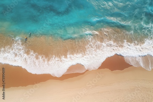 Aerial view of beach waves crashing onto the sandy shore with a person walking.