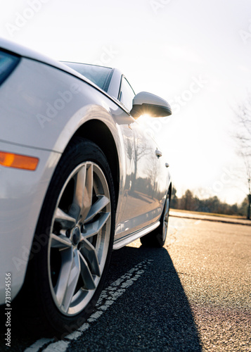 Low angle of a white car with sunshine coming over the rear view mirror