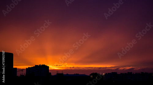 Vibrant Cityscape at Sunset with Dark Clouds and Warm Glow Behind Tall Buildings