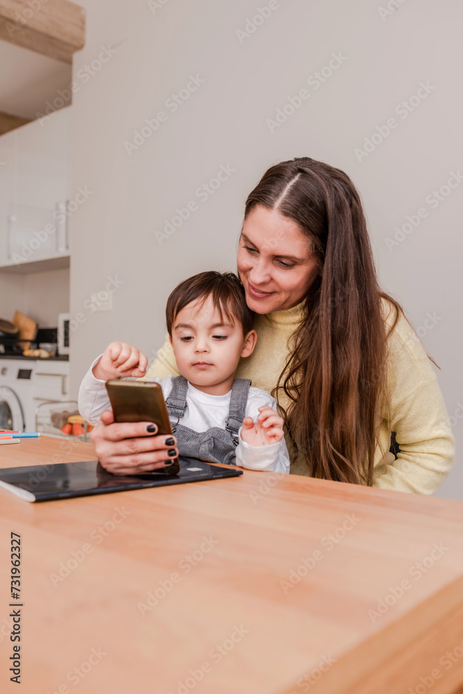 vertical portrait of smiling mother showing her little boy how to use a smartphone. Technology addiction for children concept vertical portrait of smiling mother showing her little boy how to use a smartphone. Technology addiction for children concept