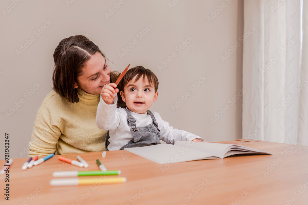 happy toddler boy learning to draw with markers with his mother at home happy toddler boy learning to draw with markers with his mother at home