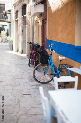 A quaint blue bike rests in the charming confines of a narrow Greek street, adding a touch of Mediterranean allure.