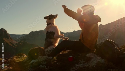 Hiker man sitting on the mountain with his border collie dog. Dog doing tricks. Dog owner sharing his food with his pet. photo