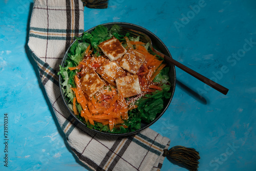 green salad with carrot and pan fried  halloumi cheese, kitchen textile napkin, served on blue textured background photo