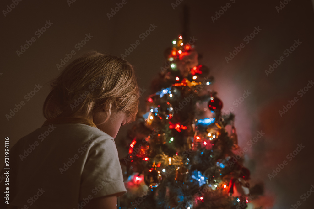 Little child near the Christmas tree with a garland Little child near the Christmas tree with a garland