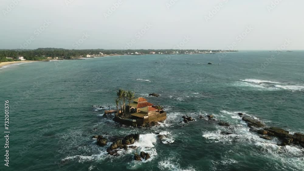 Aerial view of isolated house on small island amidst ocean waves, secluded retreat for travel, getaway, romantic vacation or eco-tourism destination. Drone footage captures unique, serene seascape. Aerial view of isolated house on small island amidst ocean waves, secluded retreat for travel, getaway, romantic vacation or eco-tourism destination. Drone footage captures unique, serene seascape.