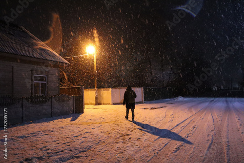Male silhouette on a snowy street with a burning lantern