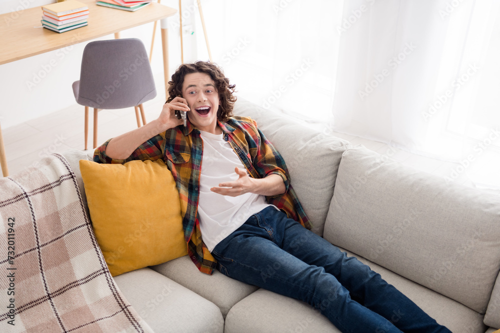 Obraz premium Photo of positive excited guy dressed checkered shirt talking modern device relaxing couch indoors house home room