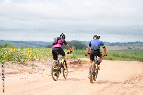 Dois ciclistas de montanha pedalando por estrada rural.