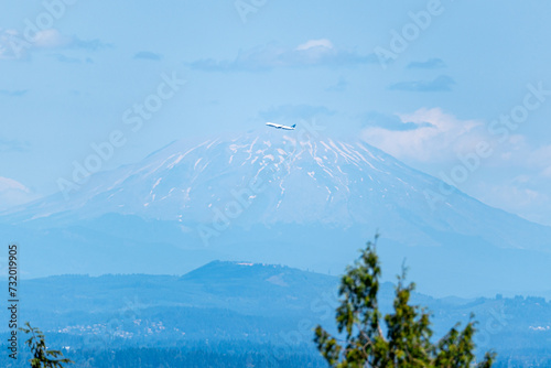 An airplane flying in front of Mount Saint Helens as viewed from Portland Oregon. photo