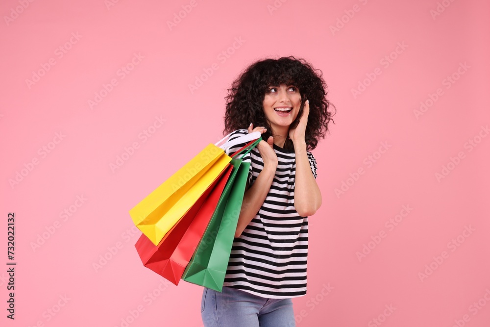 Happy young woman with shopping bags on pink background Happy young woman with shopping bags on pink background