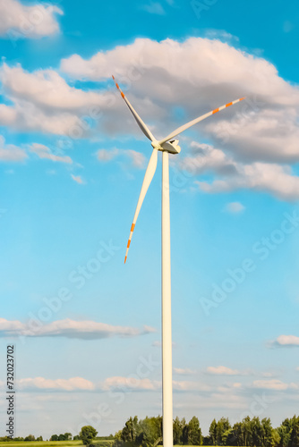 Wind Turbine Generating Clean Energy on Green Field Under Blue Sky.
