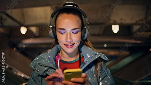 Brunette listening music wireless headphones at night walk close up. Happy woman photo