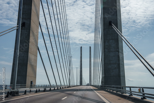 Capturing the sleek engineering of the Oresund Bridge, this image features its towering concrete supports and harplike cables under a clear blue sky, on a trafficfree multilane highway. photo