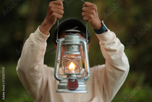 A girl was walking in the forest with a kerosene lantern in his hand.