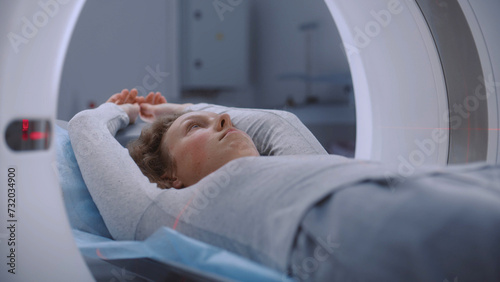 Foto Close up portrait shot of woman lying on CT or PET or MRI scan bed and moving inside machine