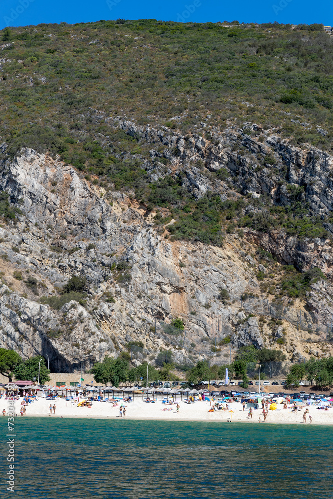Setubal, Portugal. 14 August 2023. Beach: “Praia da Figueirinha Portugal” next to the mouth of the Sado River. Parque Natural da Arrábida, Cliffs and forest in the background.