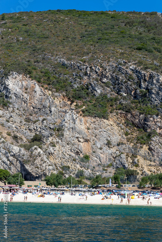 Setubal, Portugal. 14 August 2023. Beach: “Praia da Figueirinha Portugal” next to the mouth of the Sado River. Parque Natural da Arrábida, Cliffs and forest in the background. photo