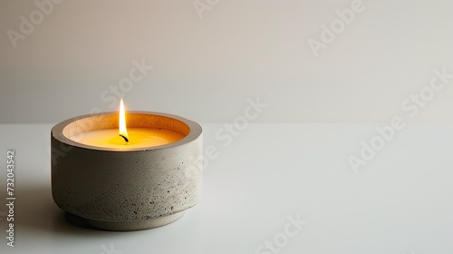 Stylish decor: Candle in a concrete candlestick on a white background. Modern design for ambient lighting