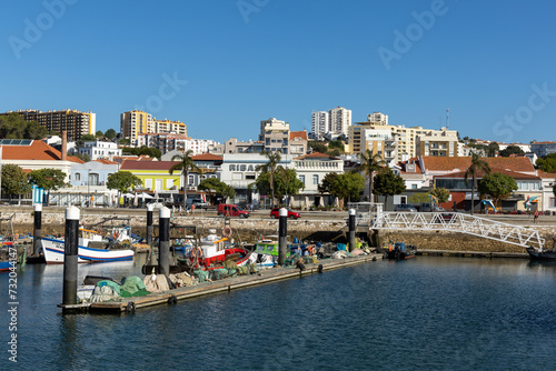 Setubal, Portugal. 14 August 2023. Fishers boats in the Port of Setúbal with the boulevard and cityscape in the background on a sunny day.
