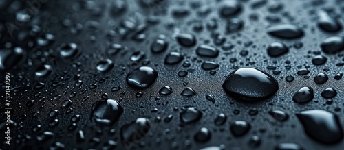 A close-up of water drops, liquid, or moisture on a black surface, showcasing the beauty of tiny droplets. photo