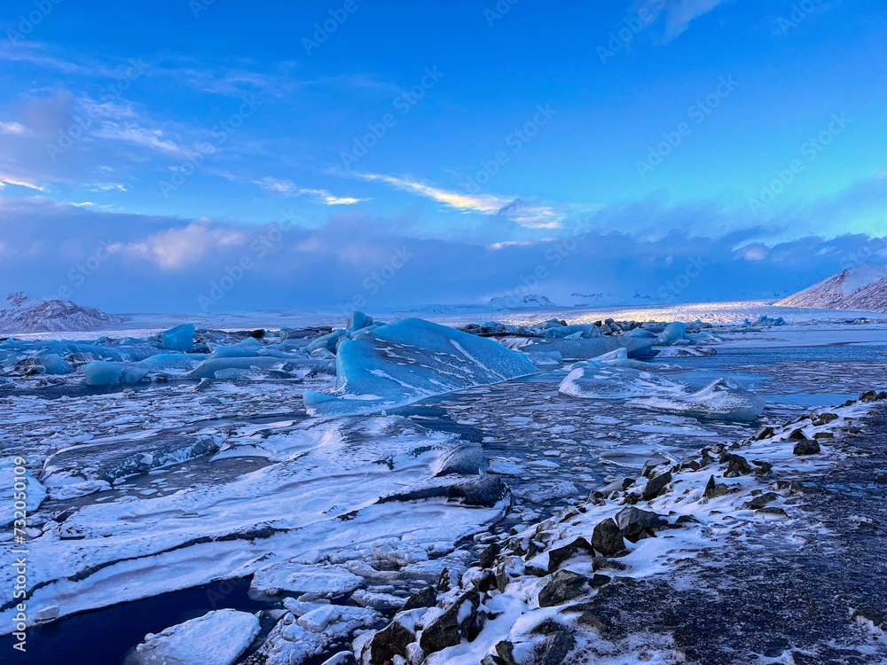 Naklejka premium Icebergs swimming at the famous glacier lagoon around Vatnajokull National Park during winter around sunset time 