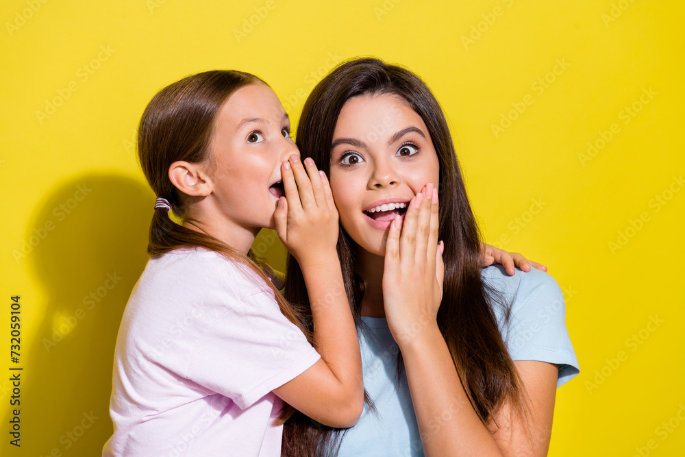 Photo of charming impressed little sisters wear t-shirts arms lips telling secrets empty space isolated yellow color background Photo of charming impressed little sisters wear t-shirts arms lips telling secrets empty space isolated yellow color background