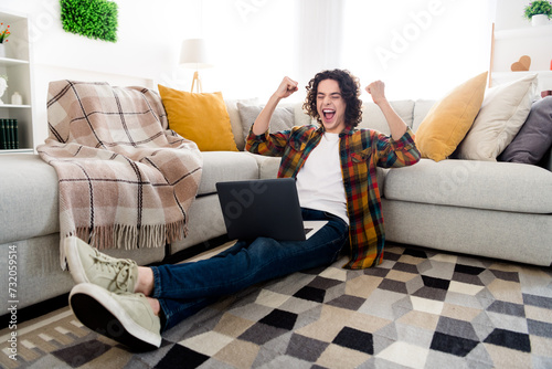 Full length photo of positive lucky guy wear plaid shirt rising fists winning game modern device indoors room home house © deagreez
