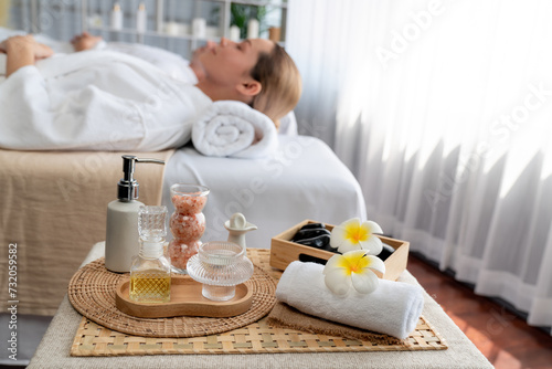 Aromatherapy massage on daylight ambiance or spa salon composition setup with focus decor and spa accessories on blur woman enjoying blissful aroma spa massage in resort or hotel background. Quiescent