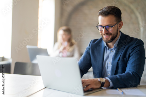 Smiling manager working on laptop at desk
