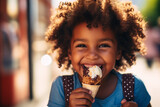 Little charming happy black boy eating cool ice cream and looking at camera outdoors in summer