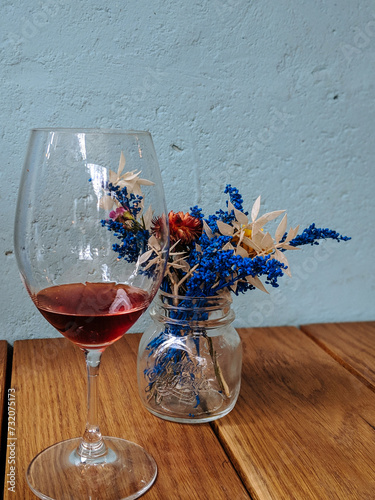 Glass of red wine next to dried flowers