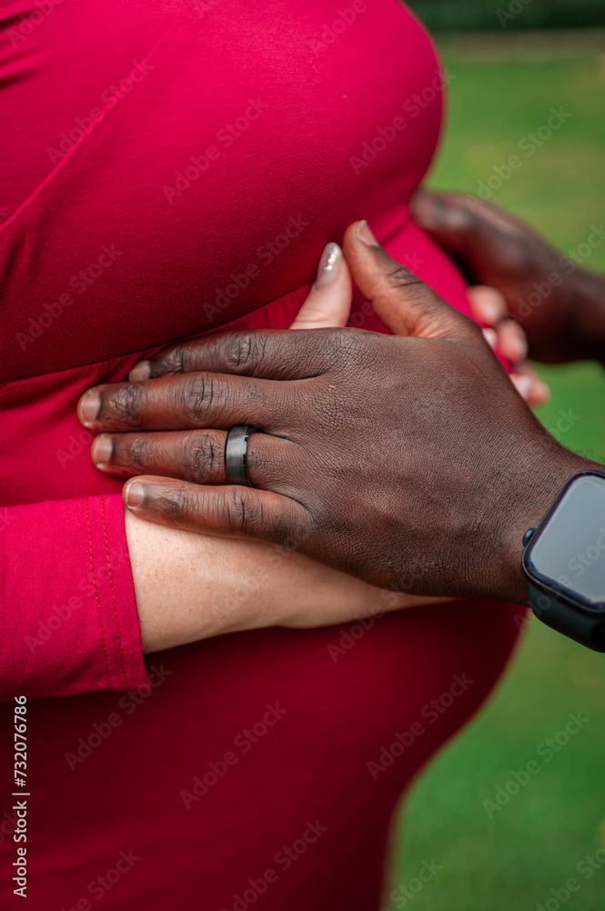 Multinational couple expecting a baby. Pregnant woman holds her hands on a belly with husband.